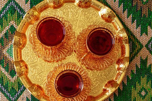 Three cups of black tea on golden oriental tray, close up