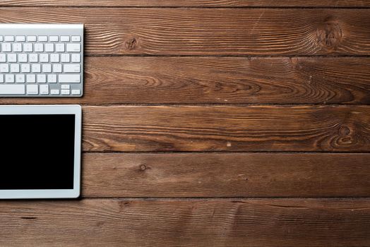 Top view of modern working place. Tablet computer and computer keyboard on vintage wooden surface. Education, creativity and innovation concept with copy space. Digital technology in modern business.