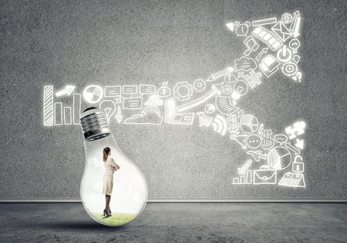 Businesswoman inside of light bulb in empty concrete room