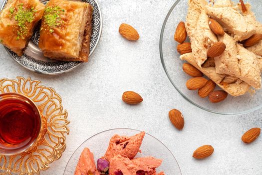 Assortment of Turkish delights with glass of tea on gray background, close up