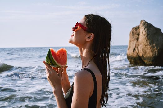 woman in black swimsuit with watermelon by the ocean. High quality photo