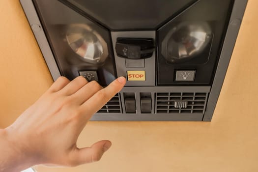 The guy's hand points his finger at the stop button of the air conditioning system in the ceiling of the tourist bus.