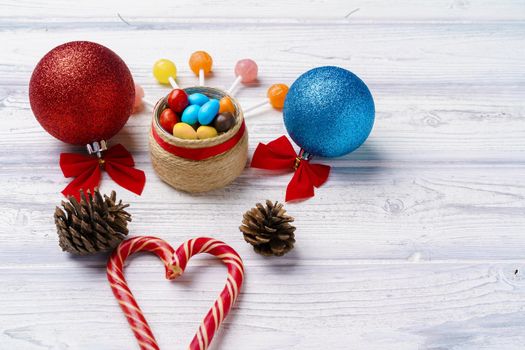 Festive background with candy canes and Christmas baubles on wooden board