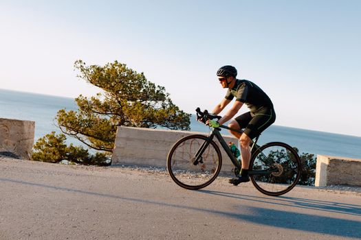 Cycling sport athlete man riding on coastal road at dawn