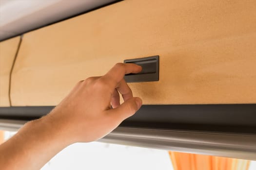 The guy's hand opens or closes the shelf for storing things in the cabin of the bus.