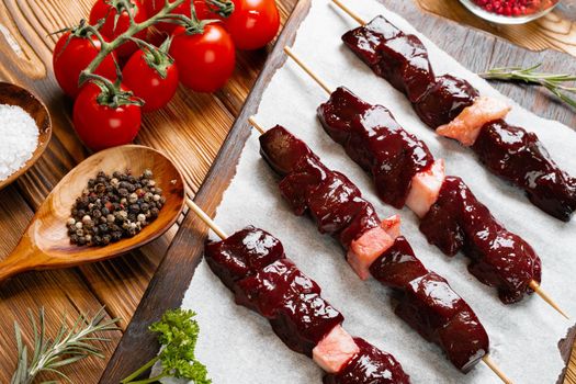 Raw kebab from meat on a wooden background with vegetables.