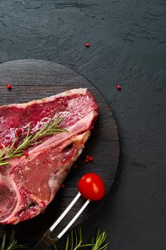 Raw t-bone steak with rosemary, pepper. Prepared for cooking. Close up.