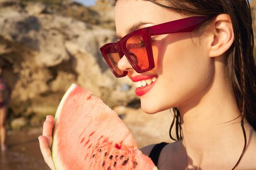 cheerful woman in sunglasses and watermelon nature rocks. High quality photo