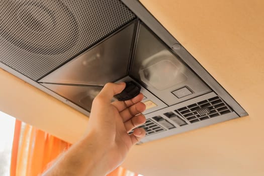 A man's hand touches the jsb in the cooling system in the ceiling of a tourist bus.