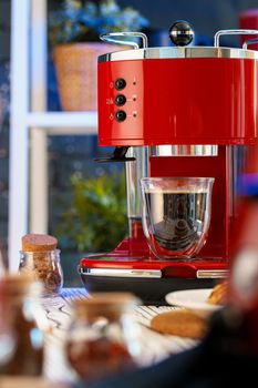 Red coffee machine with a glass on kitchen counter, close up