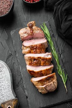 Roast duck fillet set, on stone serving board, on black stone background