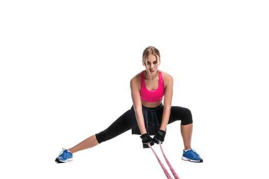 Strong woman using a resistance band in her exercise routine. Young woman performs fitness exercises on white background. Woman with beautiful slim healthy body posing in studio.