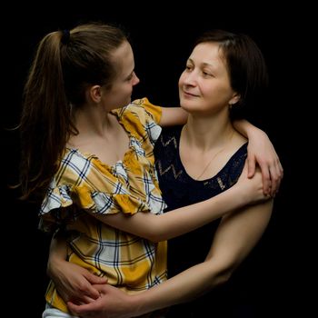 Happy family mom and little daughter, studio portrait.On black background