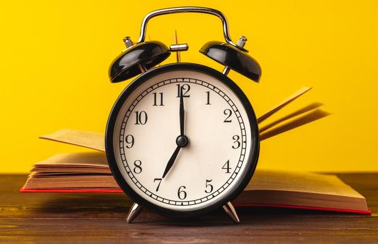 Books and alarm clock on wooden table, education concept