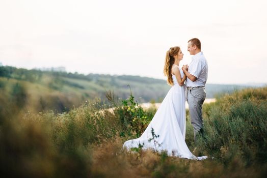 young couple a girl and a guy are walking in the field against the background of the river