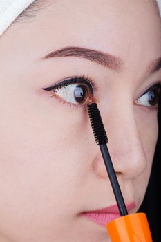 close-up woman applying mascara on her eyelashes