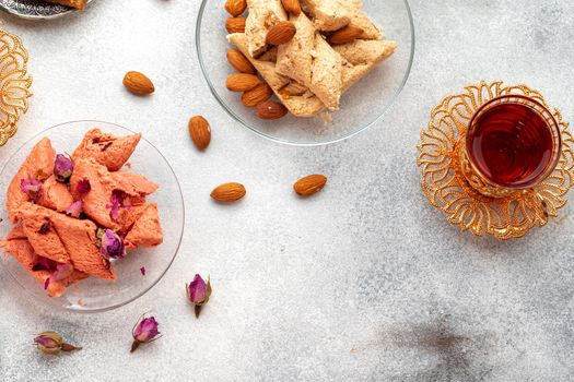 Assortment of Turkish delights with glass of tea on gray background, close up