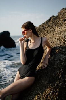 woman in swimsuit sunglasses ocean rocks posing. High quality photo