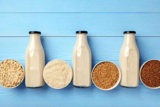 Concept of organic vegan non dairy milk with glass milk bottle and bulk products on wooden background