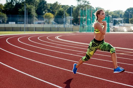 Beautiful young woman exercise jogging and running on athletic track on stadium. Red treadmill in sport field.