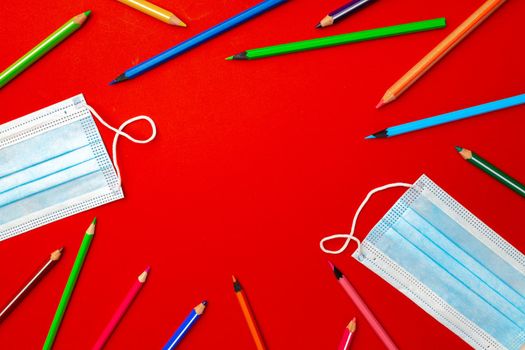 Colorful pencils and medical face mask top view. Pandemic education concept