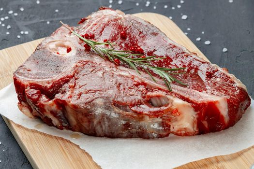 Raw fresh meat t-bone steak with spices on a dark background, close up