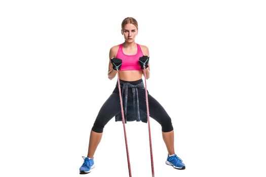 Strong woman using a resistance band in her exercise routine. Young woman performs fitness exercises on white background. Woman with beautiful slim healthy body posing in studio.