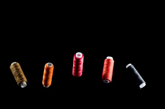 Black, bronze, orange, red and pink threads floating in the air against a black background, isolate
