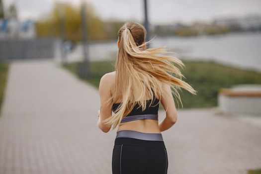 Beautiful girl training. Sports girl in a sportswear. Blonde by the water.