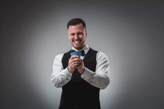 Young man in shirt and waistcoat watch his poker cards, studio shot. Poker. Emotions
