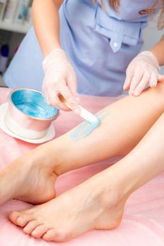 Cosmetology concept. Sugar and waxing depilation of the feet in the beauty salon. Rid of hair on the legs. Sugaring. Master cosmetologist removing hair on the legs. Beautician in the spa center.