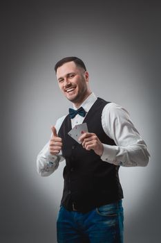 Handsome poker player with two aces in his hands. A man in the studio on a black-and-gray background