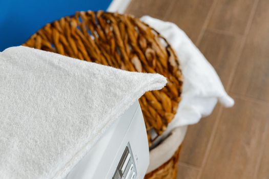 Washing machine with laundry on blue wall background, close up.