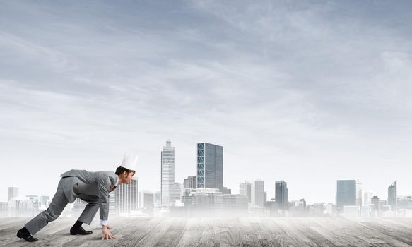 Young handsome businessman wearing white paper crown running in a hurry