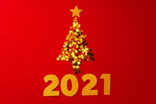 Christmas tree made of gold confetti on red background top view