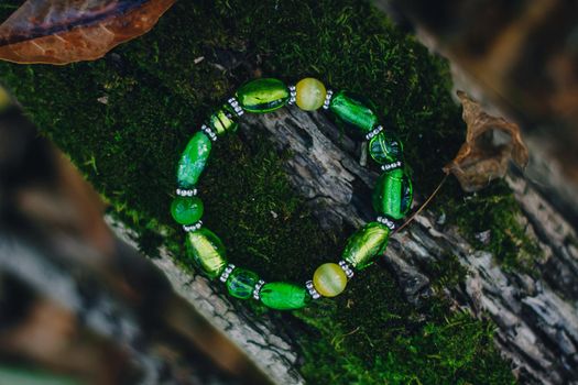 Bracelet handmade handcrafted do-it-yourself glass jewelry on natural wood forest background. Business idea, earning money for a hobby. Useful quarantined skills.