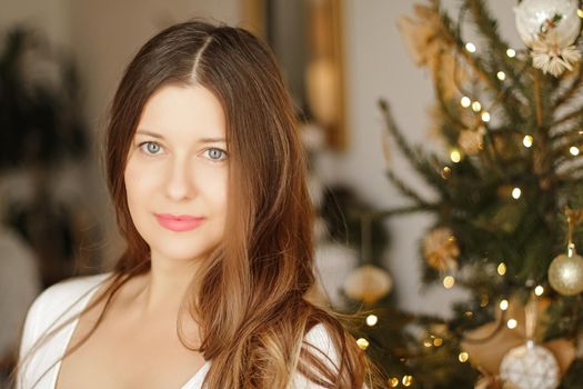 Christmas time and holiday mood concept. Happy smiling woman and decorated xmas tree lights on background.