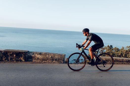 Cycling sport athlete man riding on coastal road at dawn