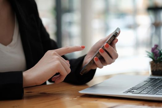 Close up hand of woman using smart phone at cafe.