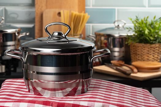 Close up of a new aluminum pot on a kitchen table with checkered napkin
