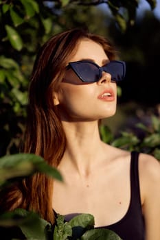 pretty woman in sunglasses in summer outdoors green leaves. High quality photo
