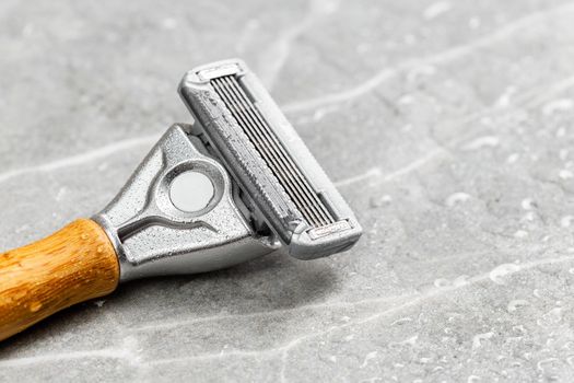 Wet shaving Razor with five blades head and wooden handle on a grey marble background. Macro shot
