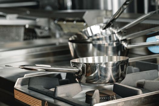 Stacked industrial metal cooking pots on proffesional kitchen close up