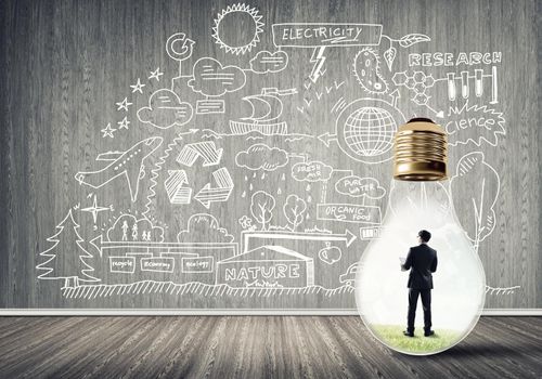 Businessman inside of light bulb in empty concrete room and sketches on wall