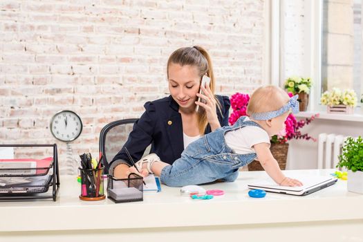 Mom and businesswoman working with laptop computer at home and playing with her baby girl. Horizontal shape, front view, waist up