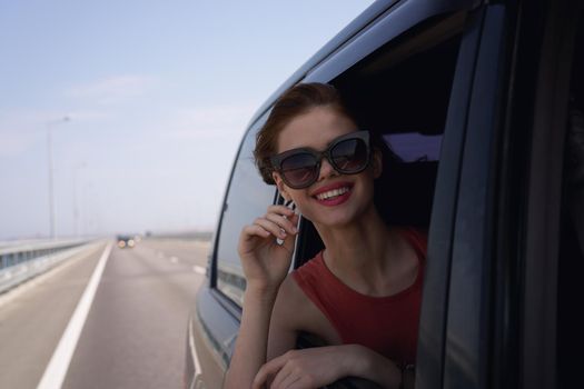 a woman is driving in a car on the road and looking out of the window. High quality photo