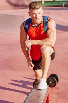 athletic man with dumbbells in his hands outdoors in the park. High quality photo