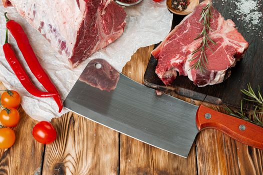 Raw T-bone steak with herbs on wooden board, close up