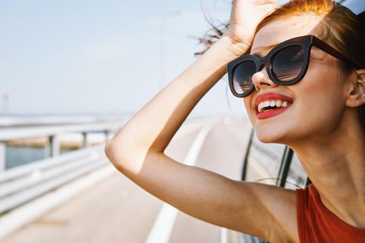 cheerful woman peeking out of the car window trip adventure lifestyle. High quality photo