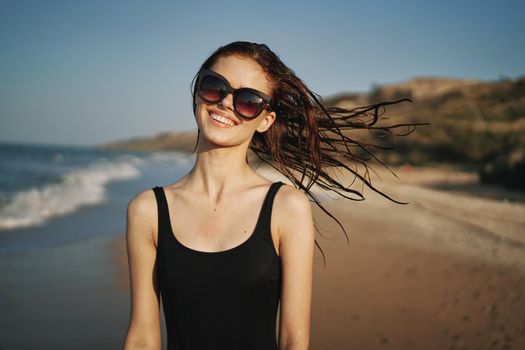 woman walks along the sandy shore in a black swimsuit sun tropics. High quality photo
